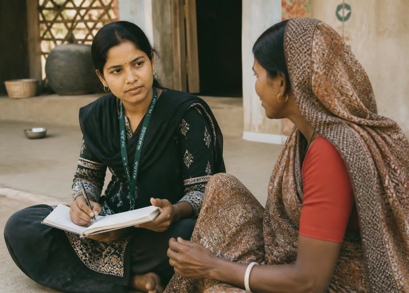 A Mehnatkash field worker listening to a woman in a village courtyard